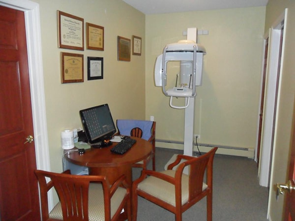 Take the virtual office tour. A consultation room at Distinctive Dentistry in Totowa, NJ with a small table with three chairs with a computer and a piece of our stat-of-the-art equipment. Our dentist accreditations are clearly displayed on the wall above the computer table. 